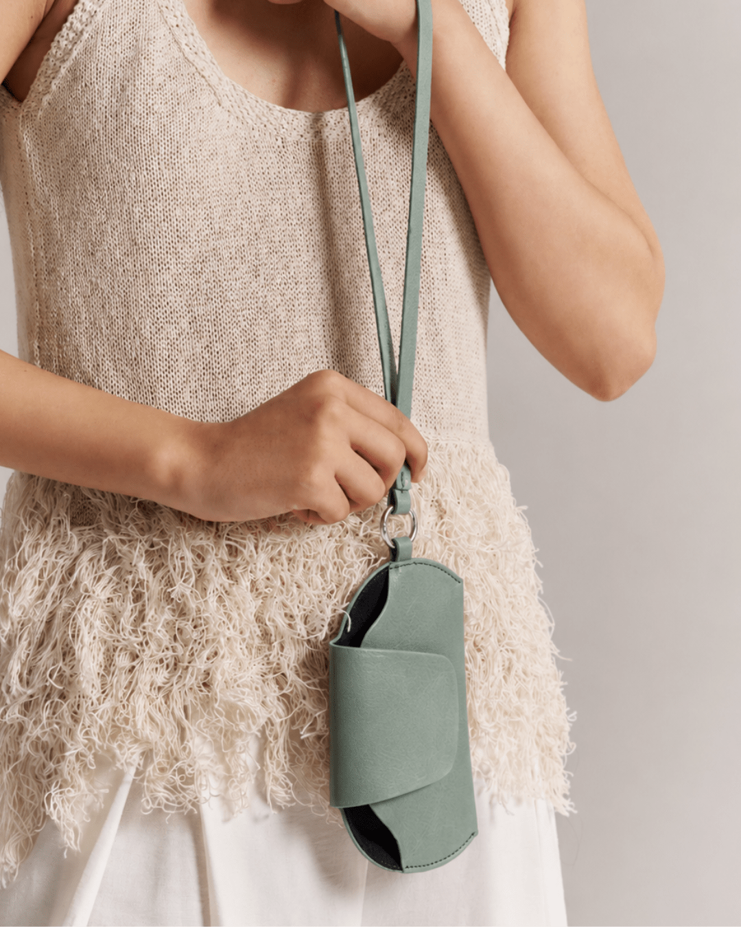 Sage green sunglasses holder worn on chest with long strap