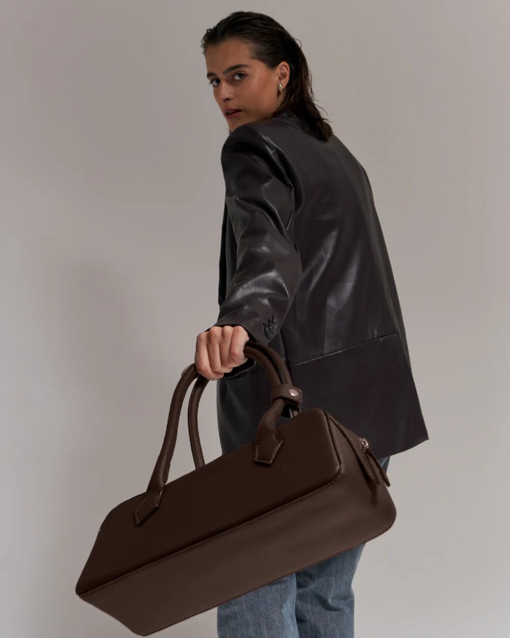 Dark brown baguette handbag in side view with two top handles