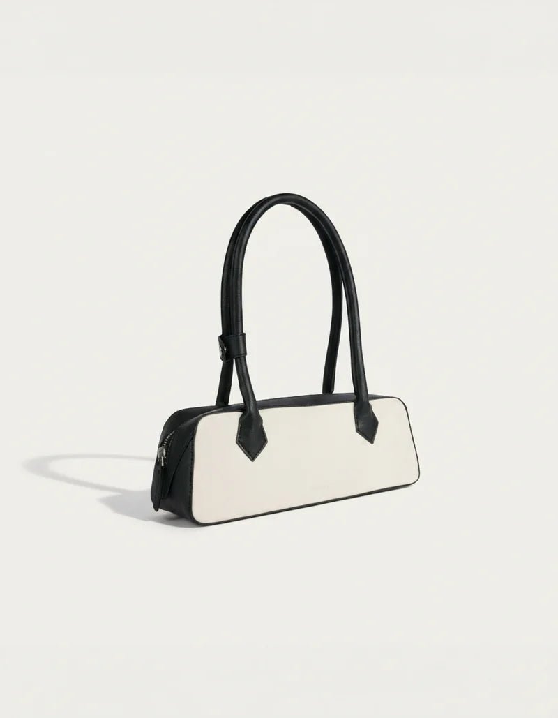 White and black structured baguette handbag with black handles and side profile
