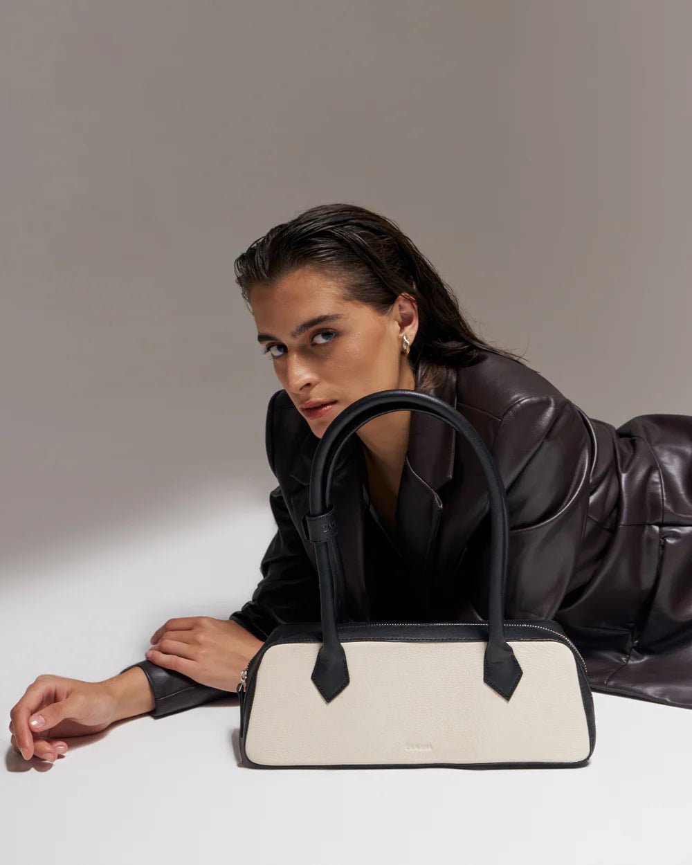White and black baguette handbag with black top handles, set on seat