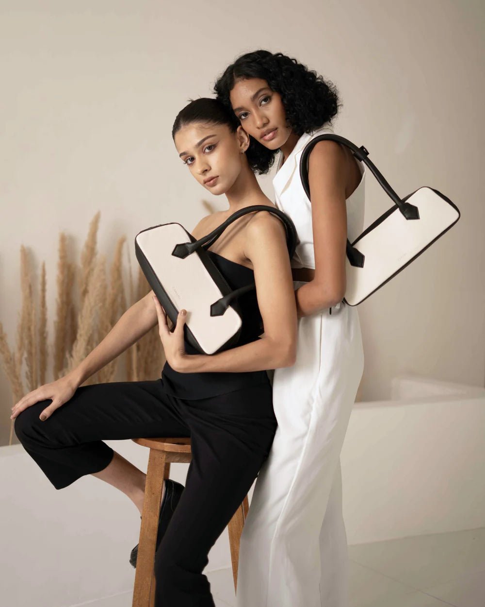 White and black baguette handbag with black handles, carried by model