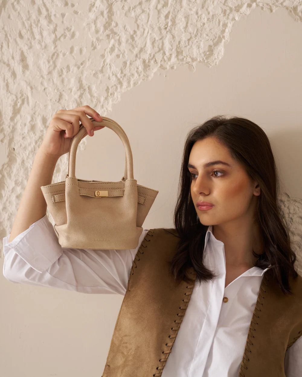 Cream tote bag held up by short handles with front buckle detail