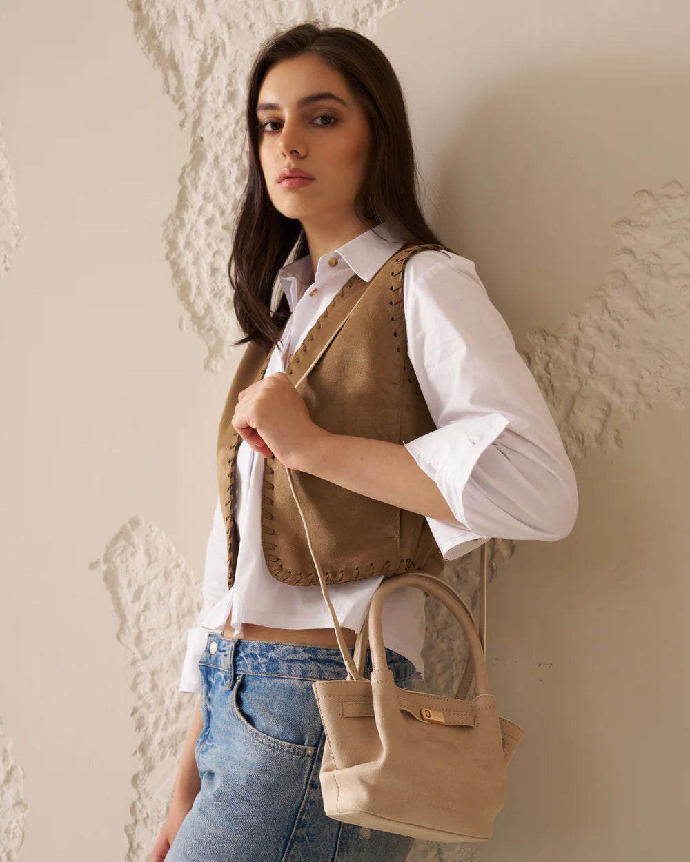 Cream tote bag with top handles and front buckle strap, carried on body