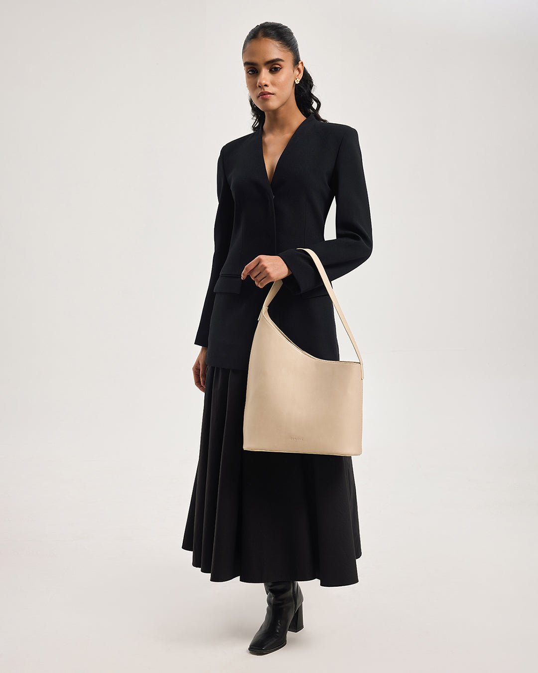 Beige hobo tote bag with long handles, carried by model in black dress