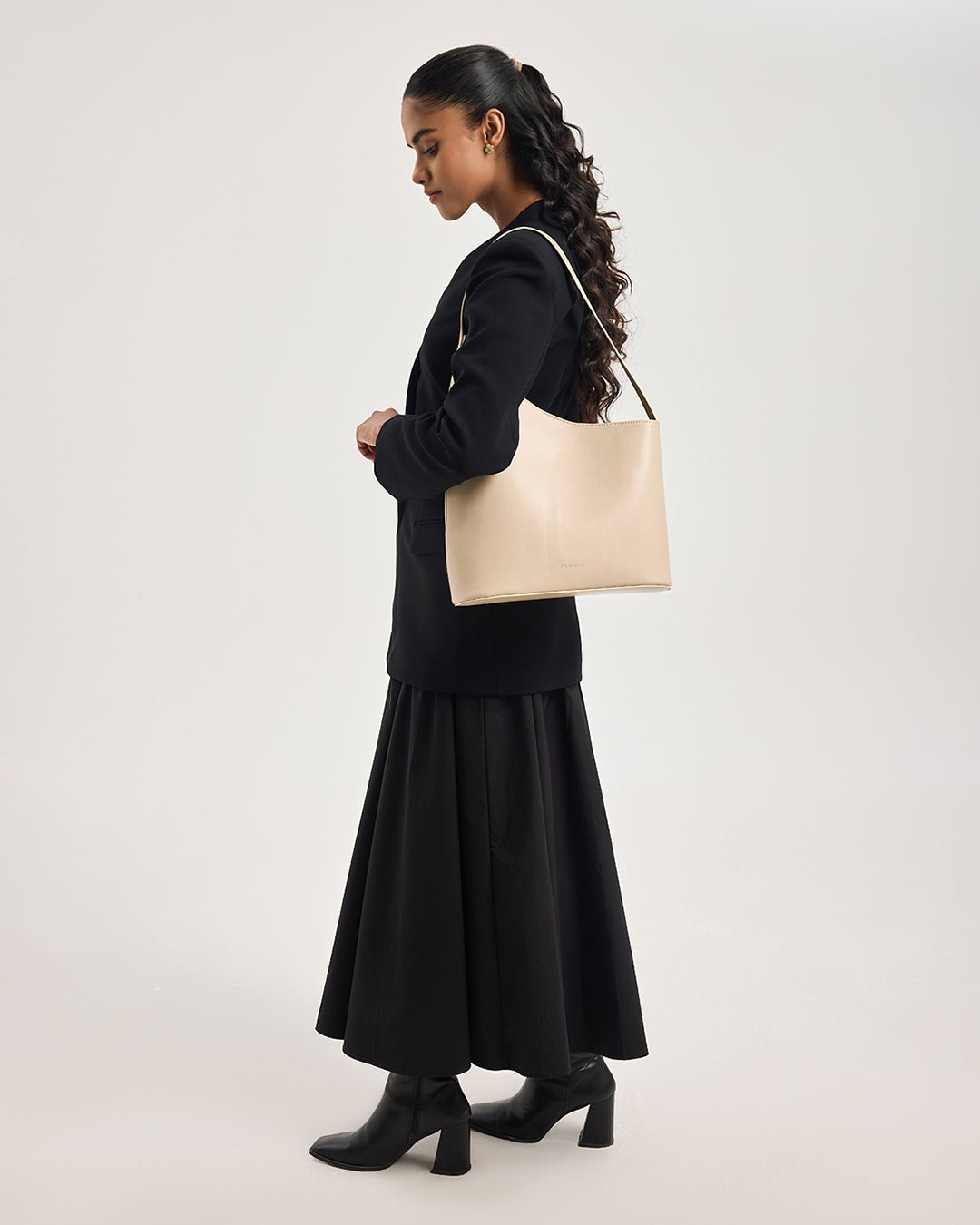 Beige hobo tote bag on shoulder with long handles, side view on model