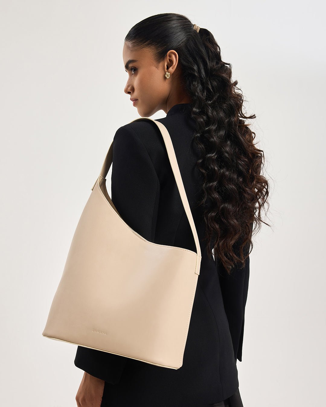 Beige hobo tote bag from side view with long handles, worn by model