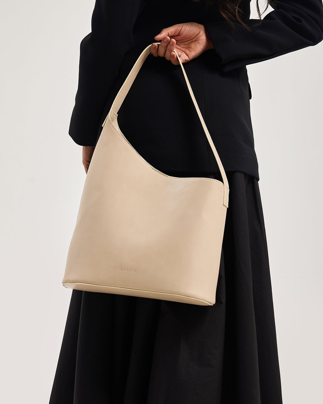 Beige hobo tote bag with long top handle and curved gusset, model holding