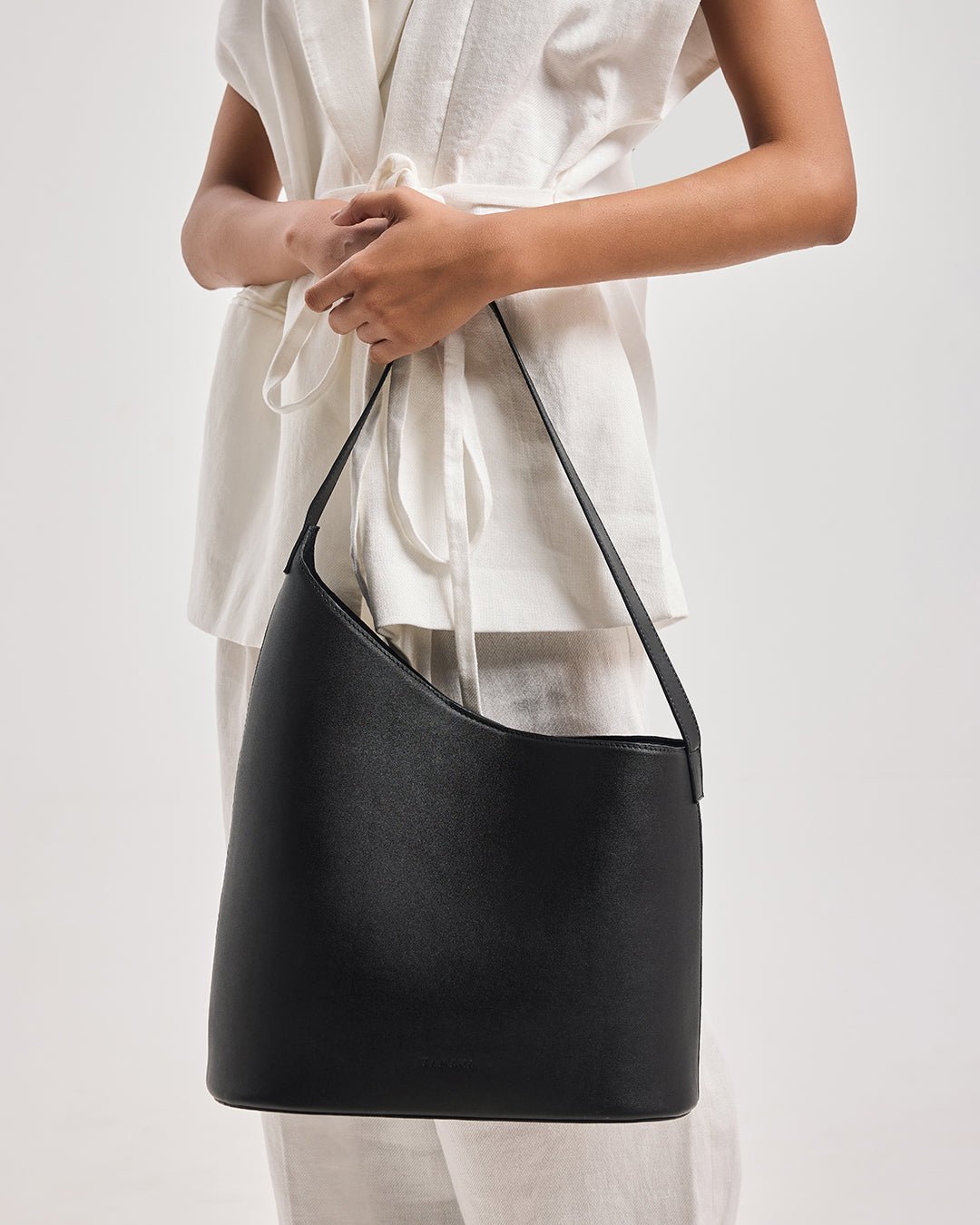 Black bucket shoulder bag with curved silhouette and long wide carrying strap