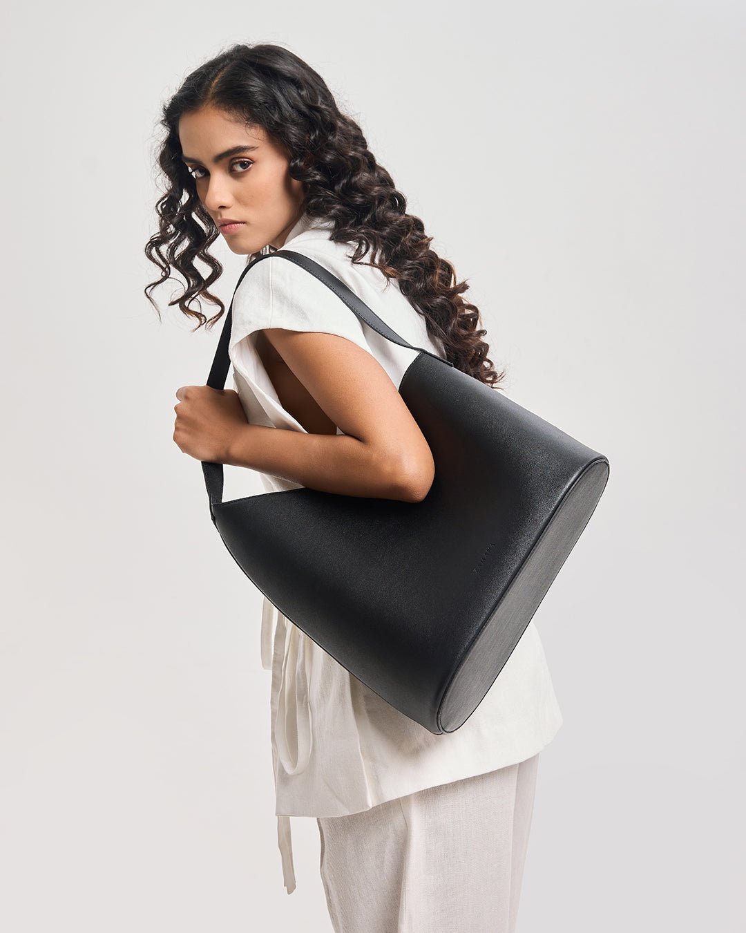 Black bucket shoulder bag with smooth finish and wide strap, side view
