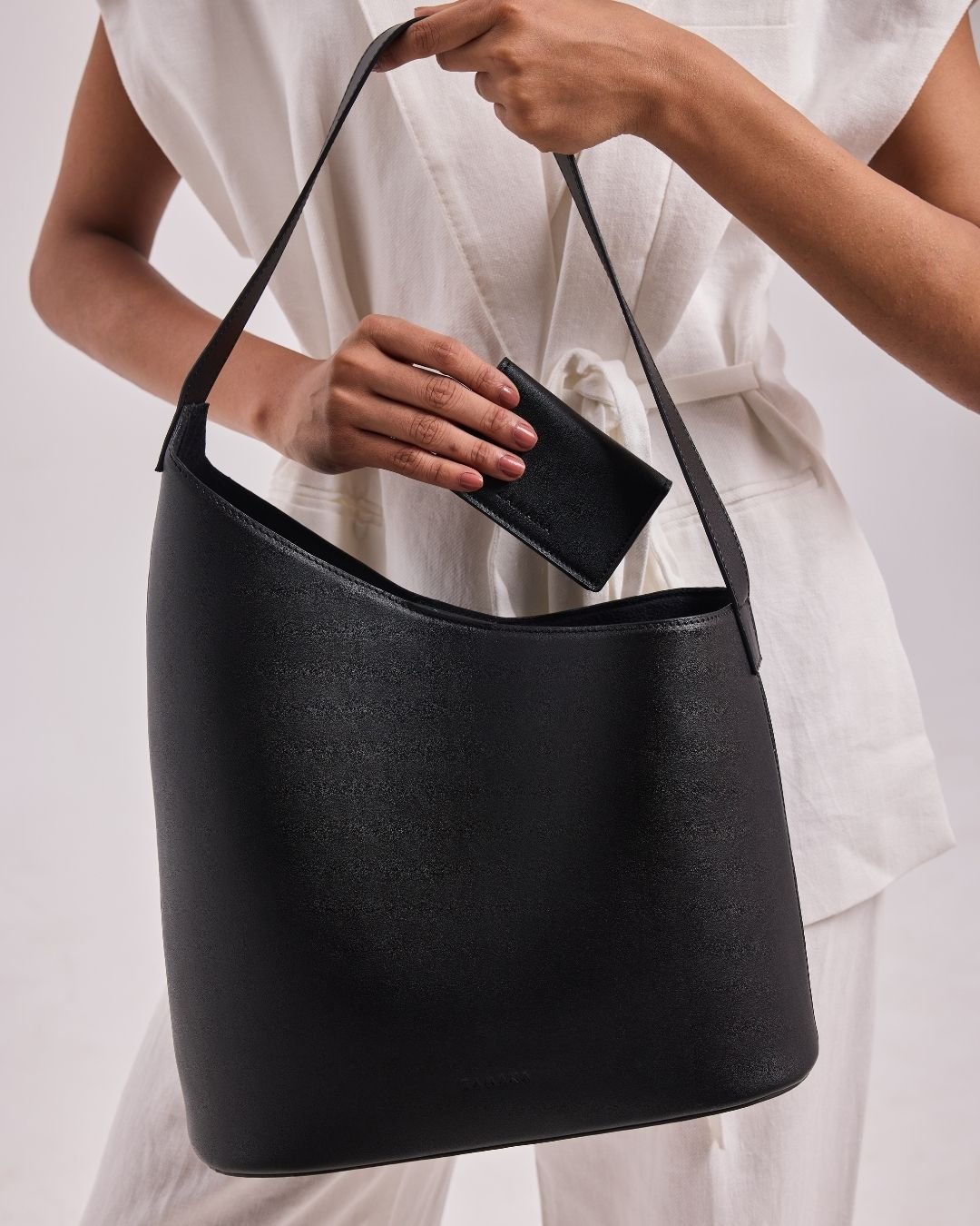 Black leather-style bucket shoulder bag with top handle and interior lining opening