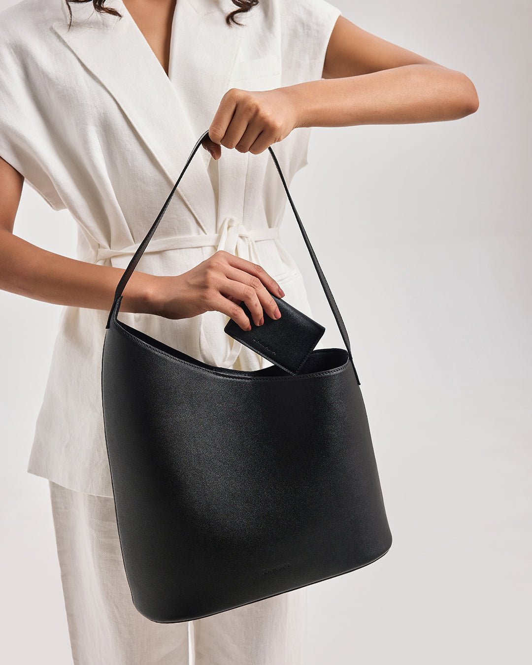 Black bucket shoulder bag with wide strap and top opening, close-up detail