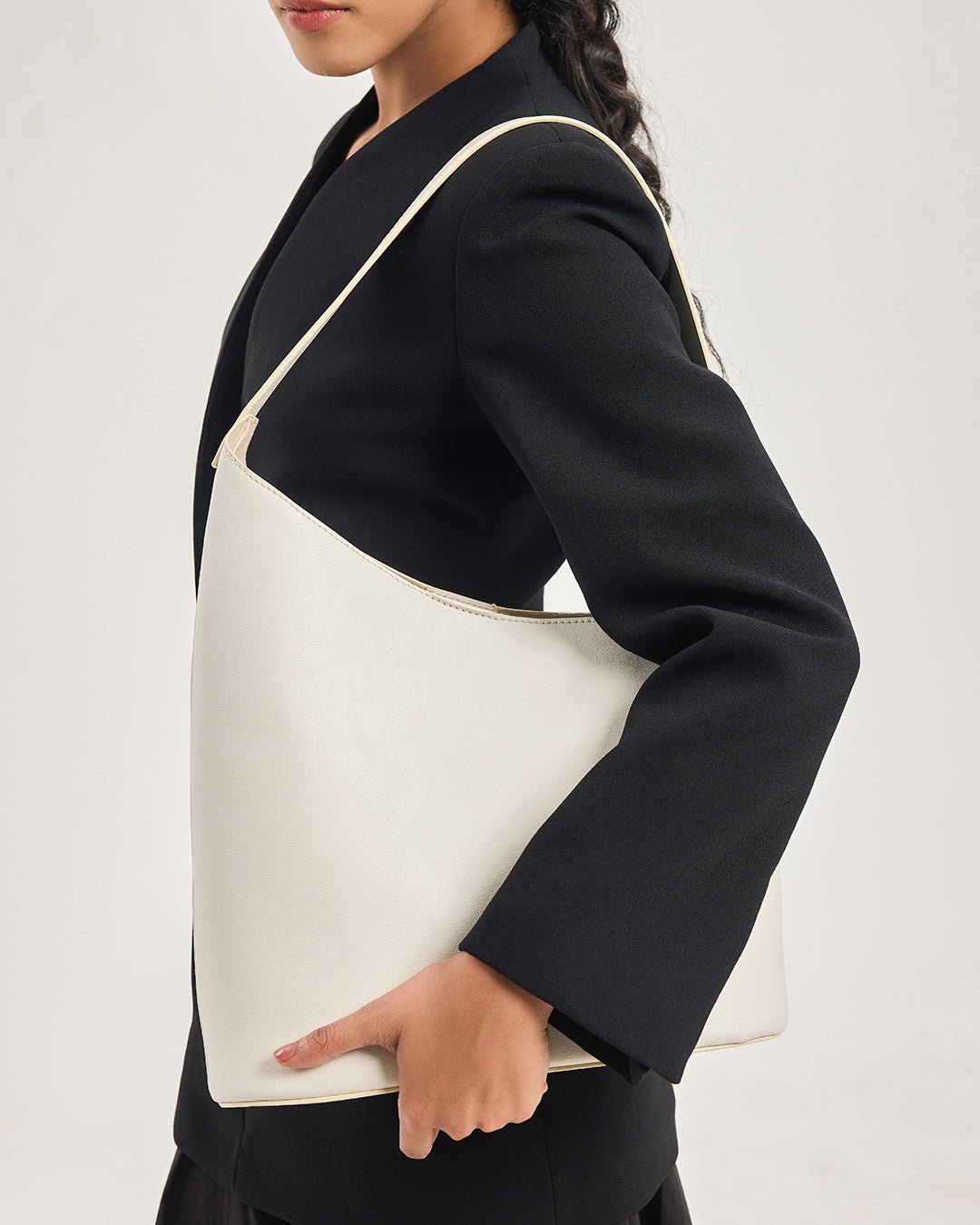 White hobo shoulder bag with tan-trim curved top and open front.