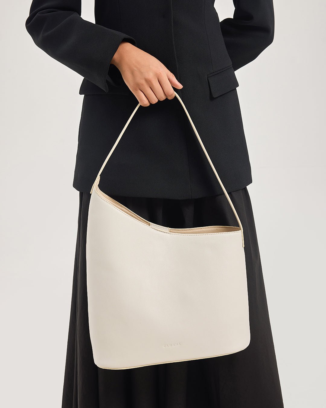 White hobo shoulder bag with long strap and tan trim, open top.