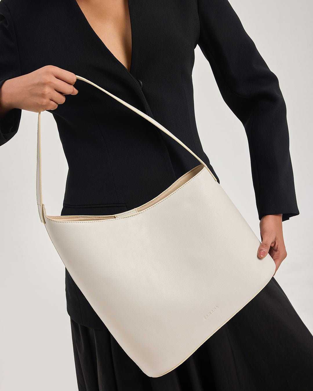 White hobo shoulder bag with wide opening and tan-trim shoulder strap.