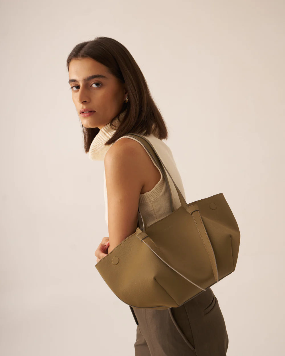 Olive tote bag with strap and structured base, model profile view