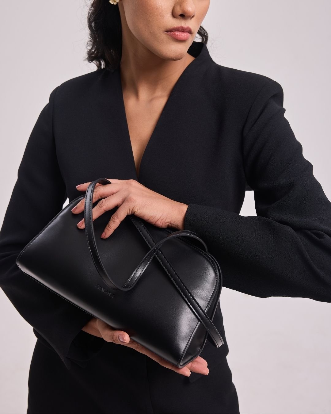 Black leather shoulder bag with double top handles and bow-style tie detail.