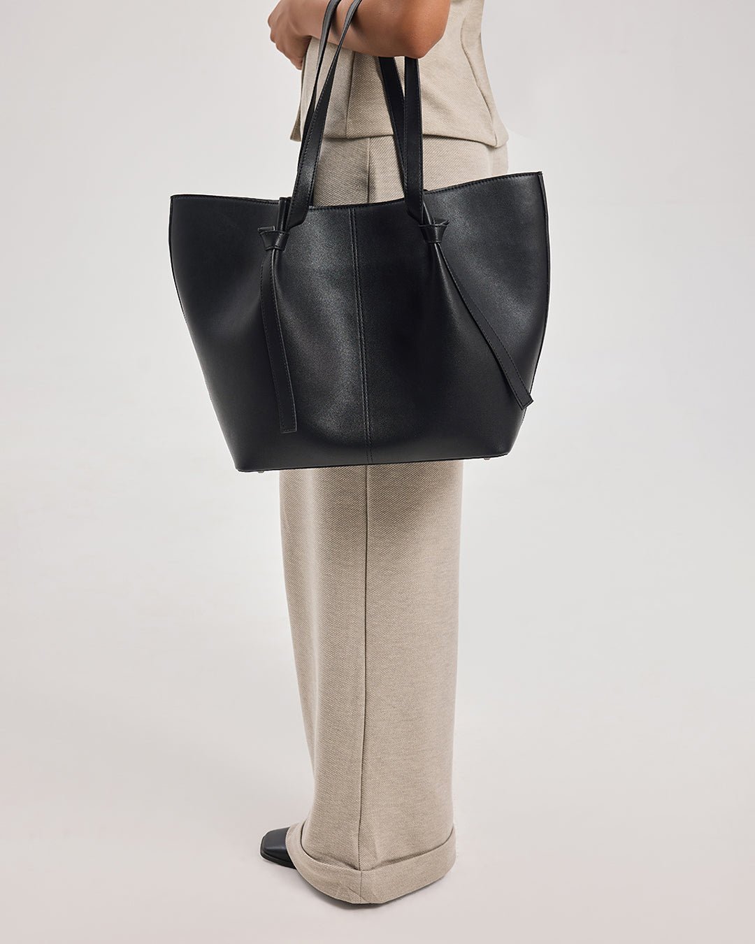 Black leather tote bag with top handles and smooth front panel