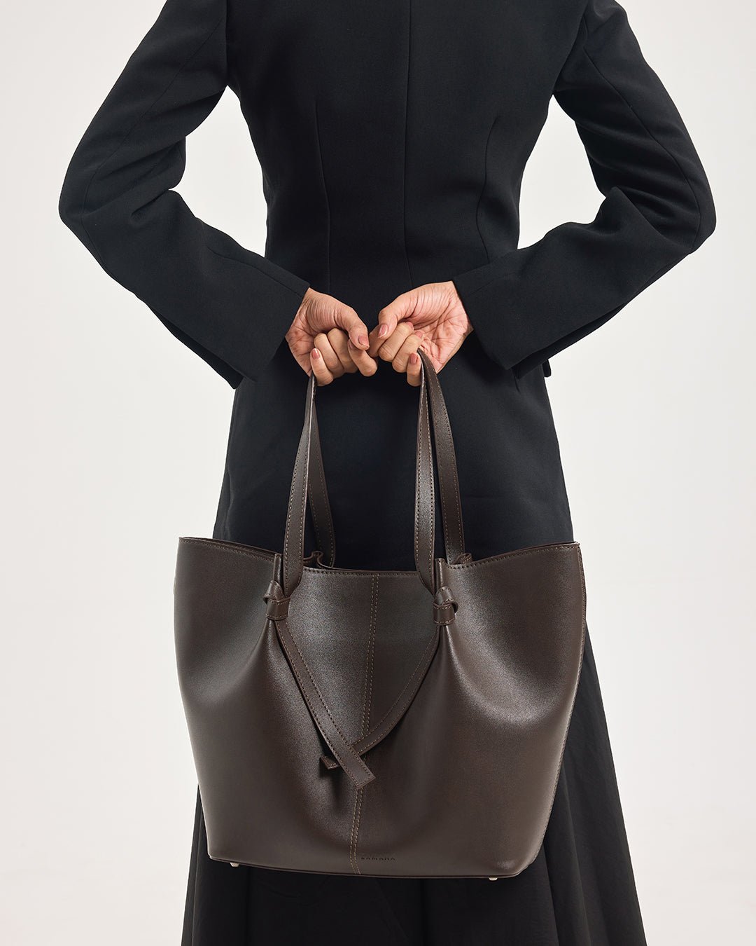 Dark brown leather tote bag with dual handles and V-shaped front strap detail.