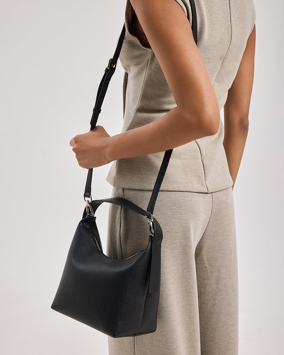 Black textured hobo bag with crossbody strap and rounded top opening