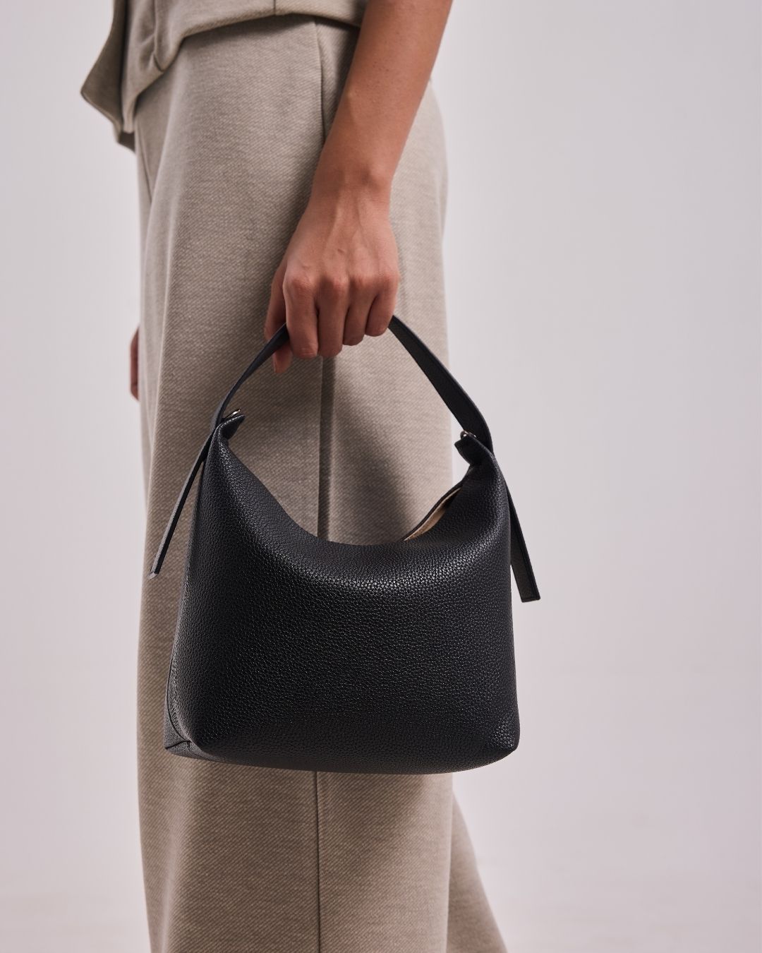 Black leather hobo shoulder bag with short handles and drawstring-style tassels