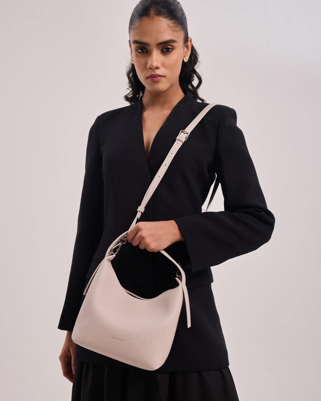 Cream hobo crossbody bag with top handle, long strap, and knotted side tassels