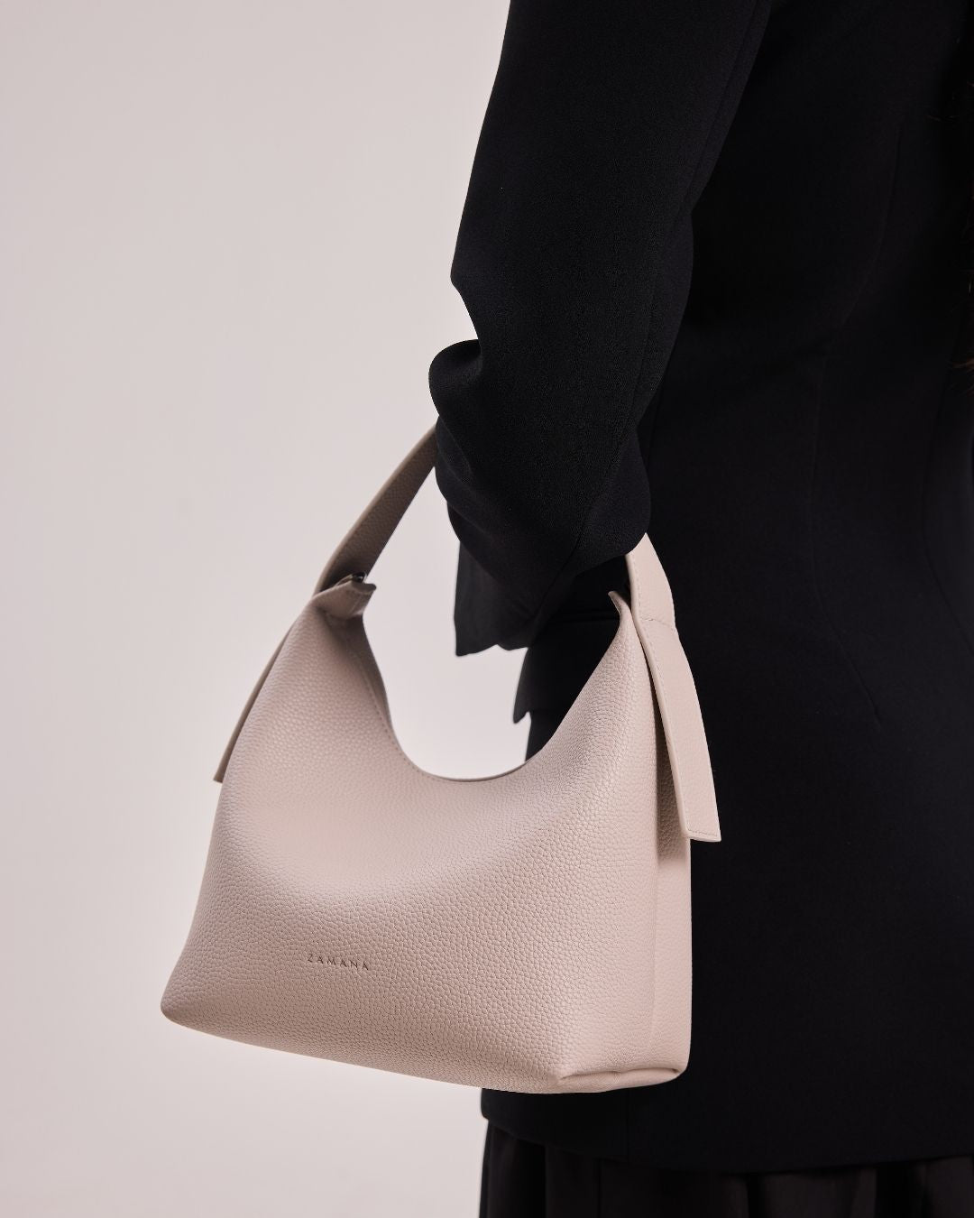 Cream hobo shoulder bag with curved handle and side tassel tie detail