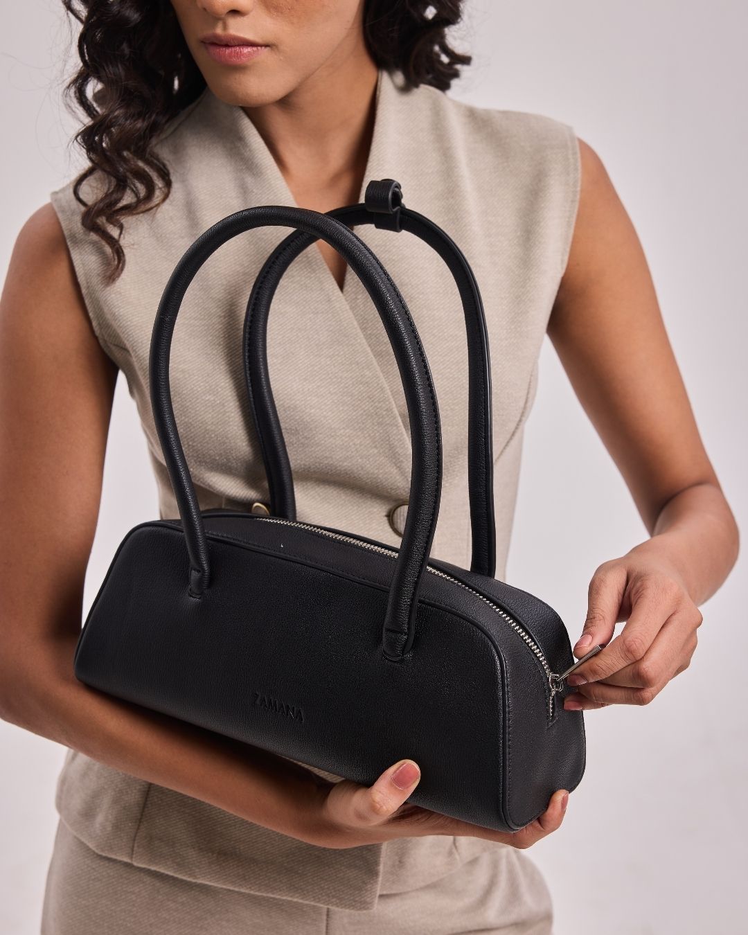 Black top-handle handbag with two handles and silver zipper on front