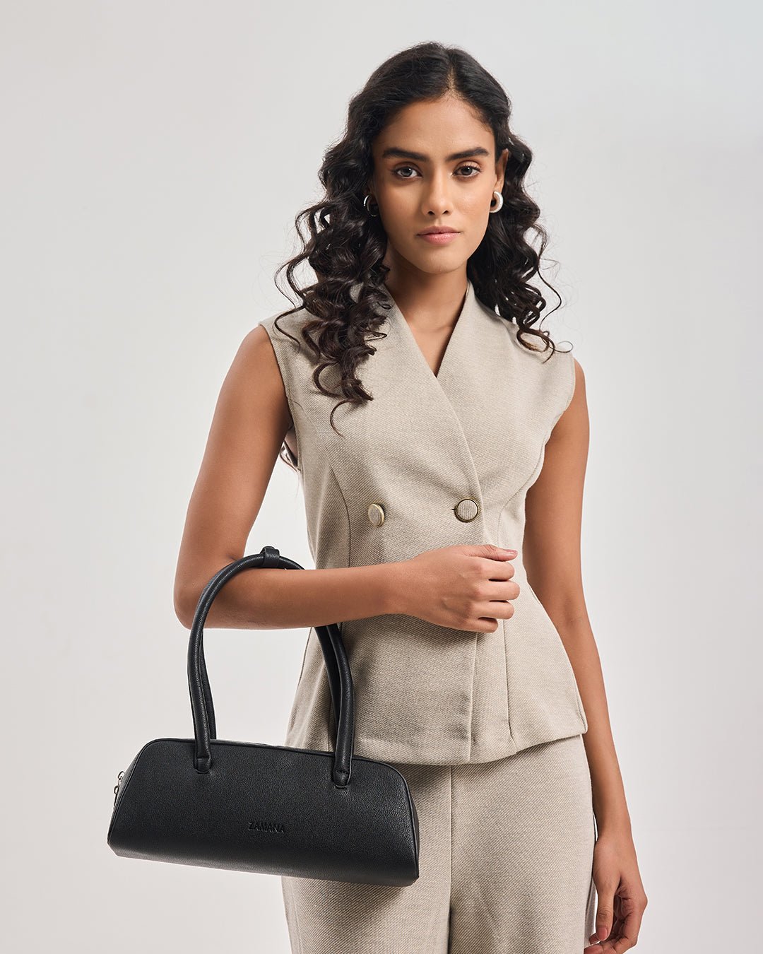 Black top-handle handbag held across body with front zipper