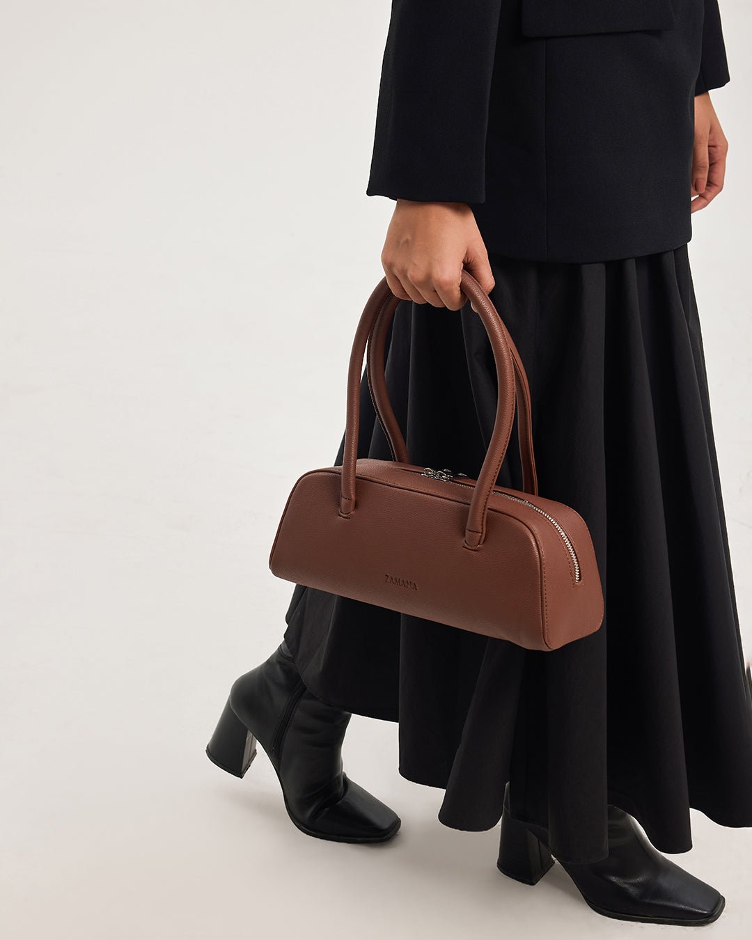 Chocolate brown top-handle handbag worn by model with zip front and handles
