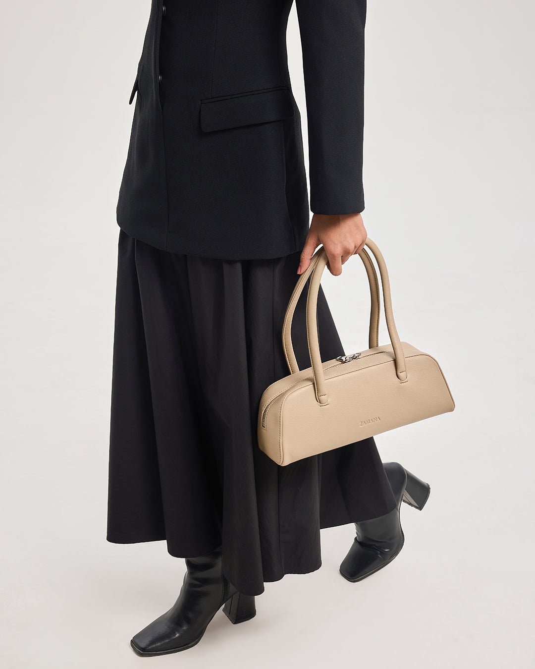 Cream handbag with double top handles and zip closure, held at side