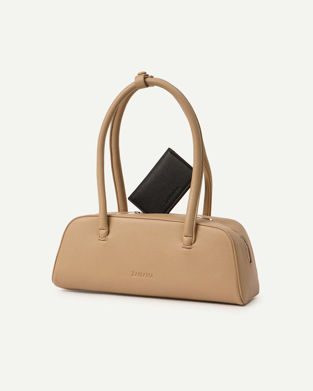 Cream/tan top-handle handbag holding a black card accessory in front