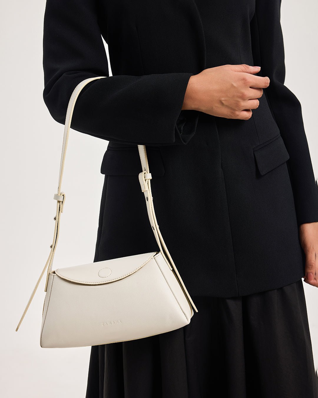 White mini shoulder bag with curved front panel, zip top, and rope shoulder strap.