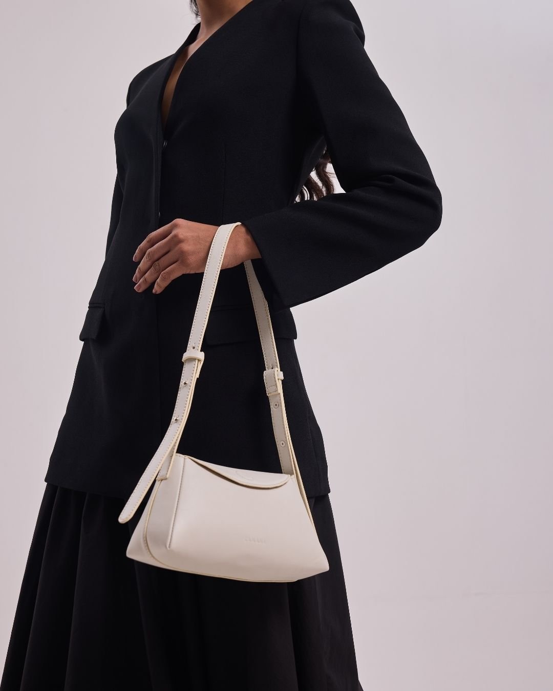 Woman carrying a white mini handbag with rope shoulder strap and short top handles.