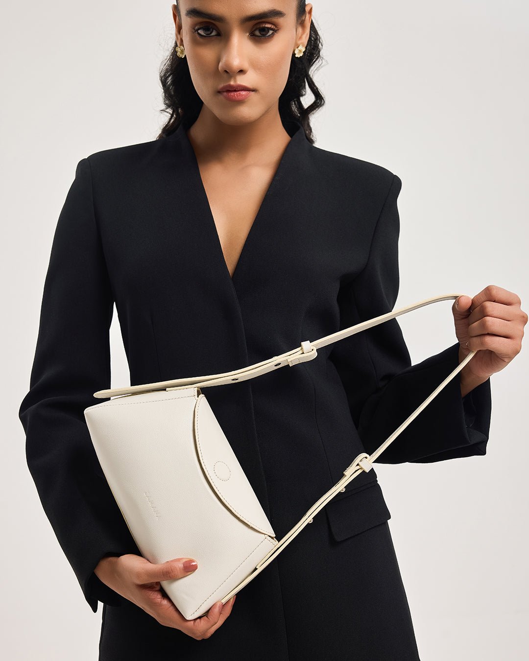 Woman holding a white mini handbag with top handles and rope shoulder strap.