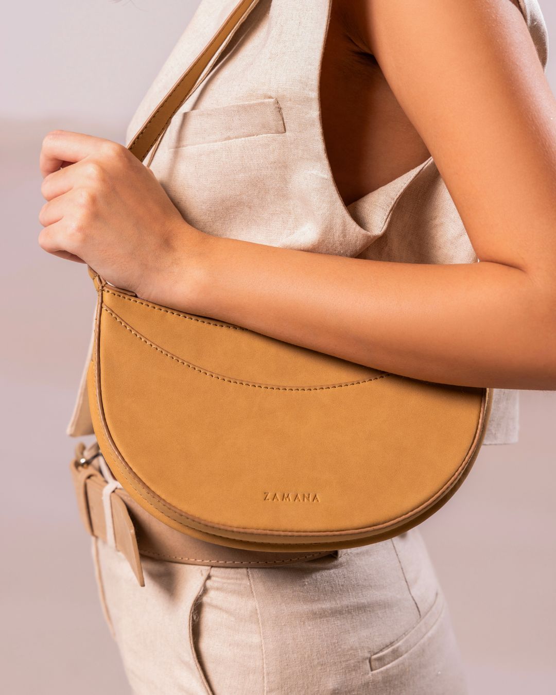 Caramel crescent crossbody bag with gold-tone hardware and long shoulder strap