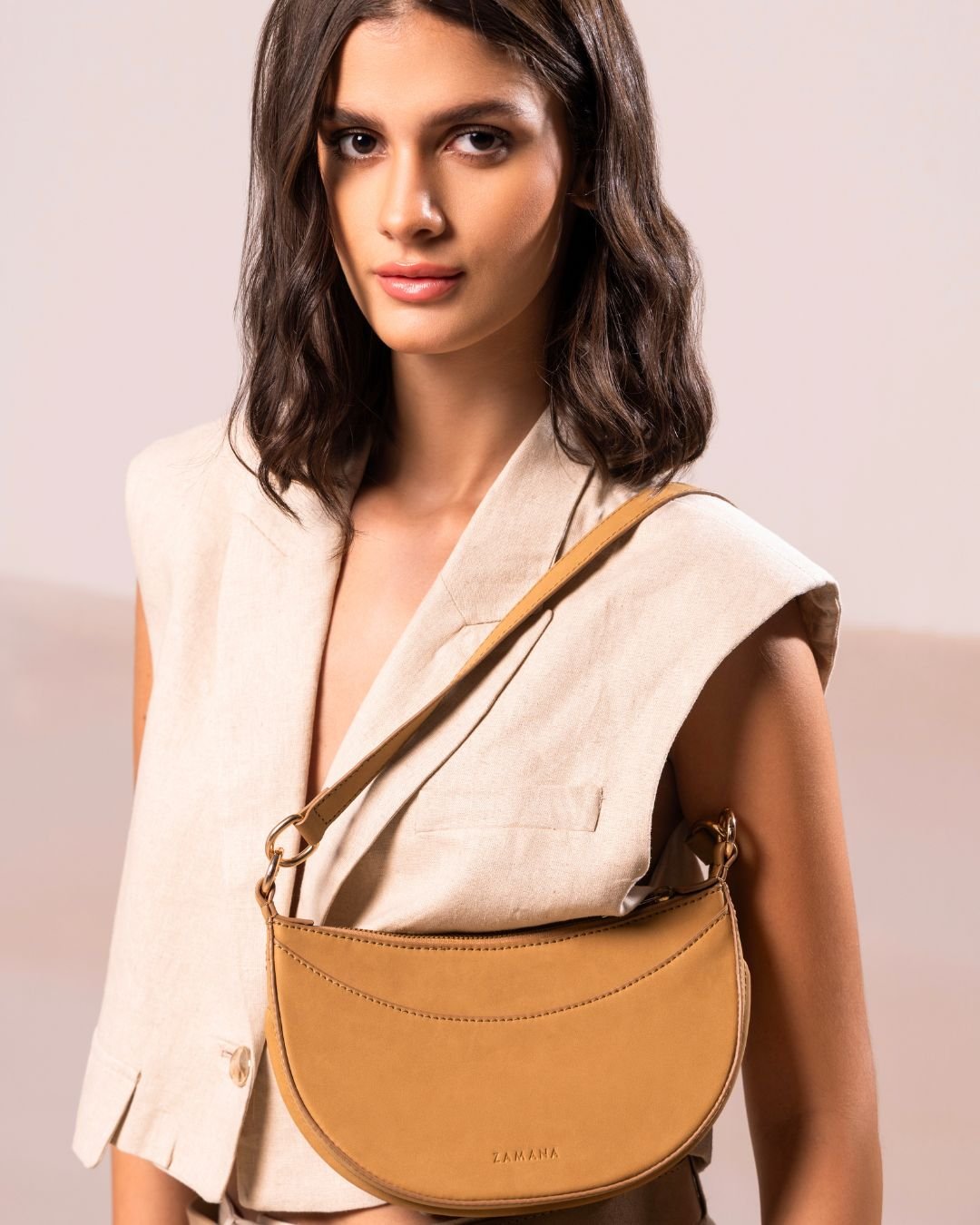Caramel crescent crossbody bag worn crossbody with adjustable shoulder strap