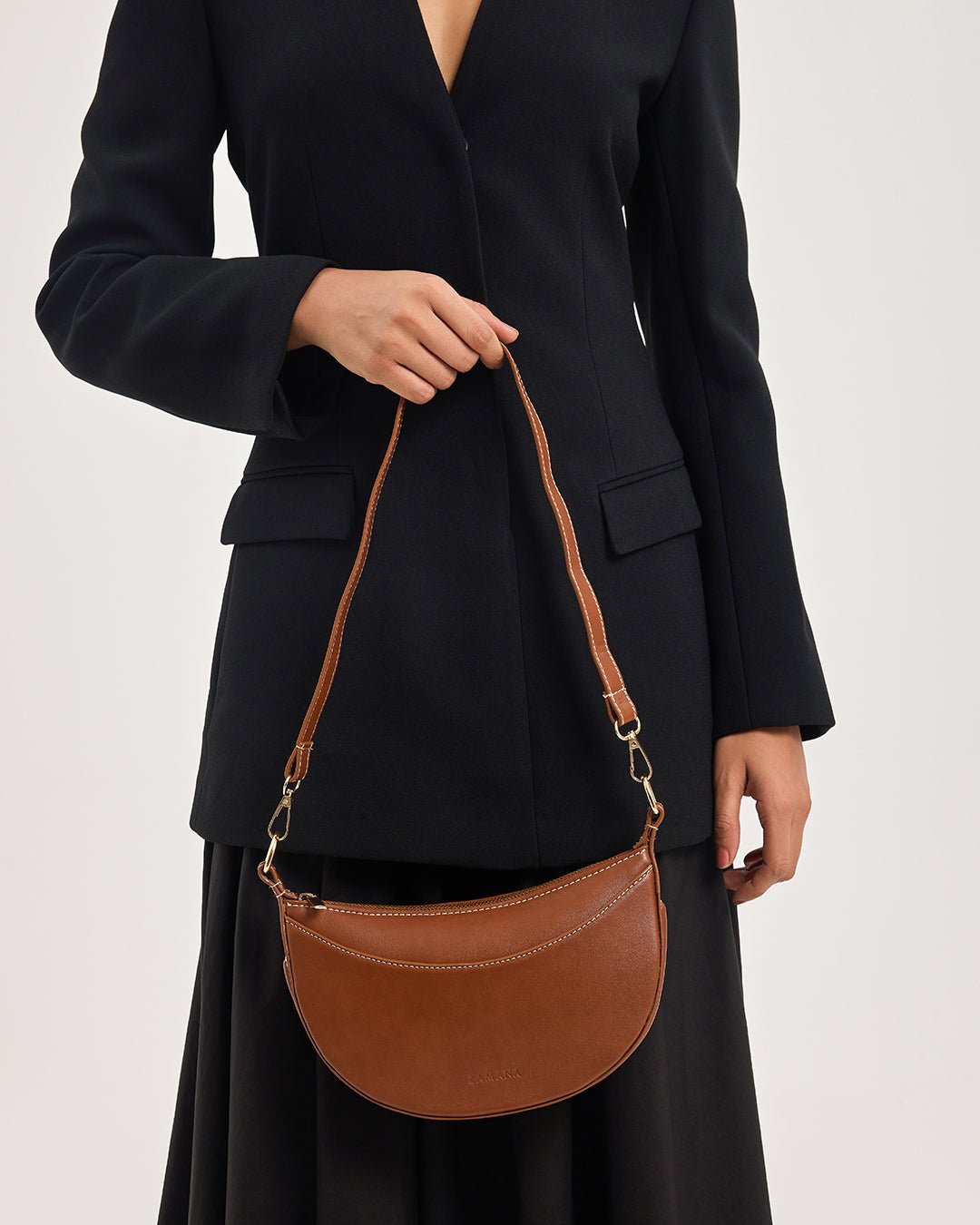 Tan half-moon crossbody bag worn on model with chain strap