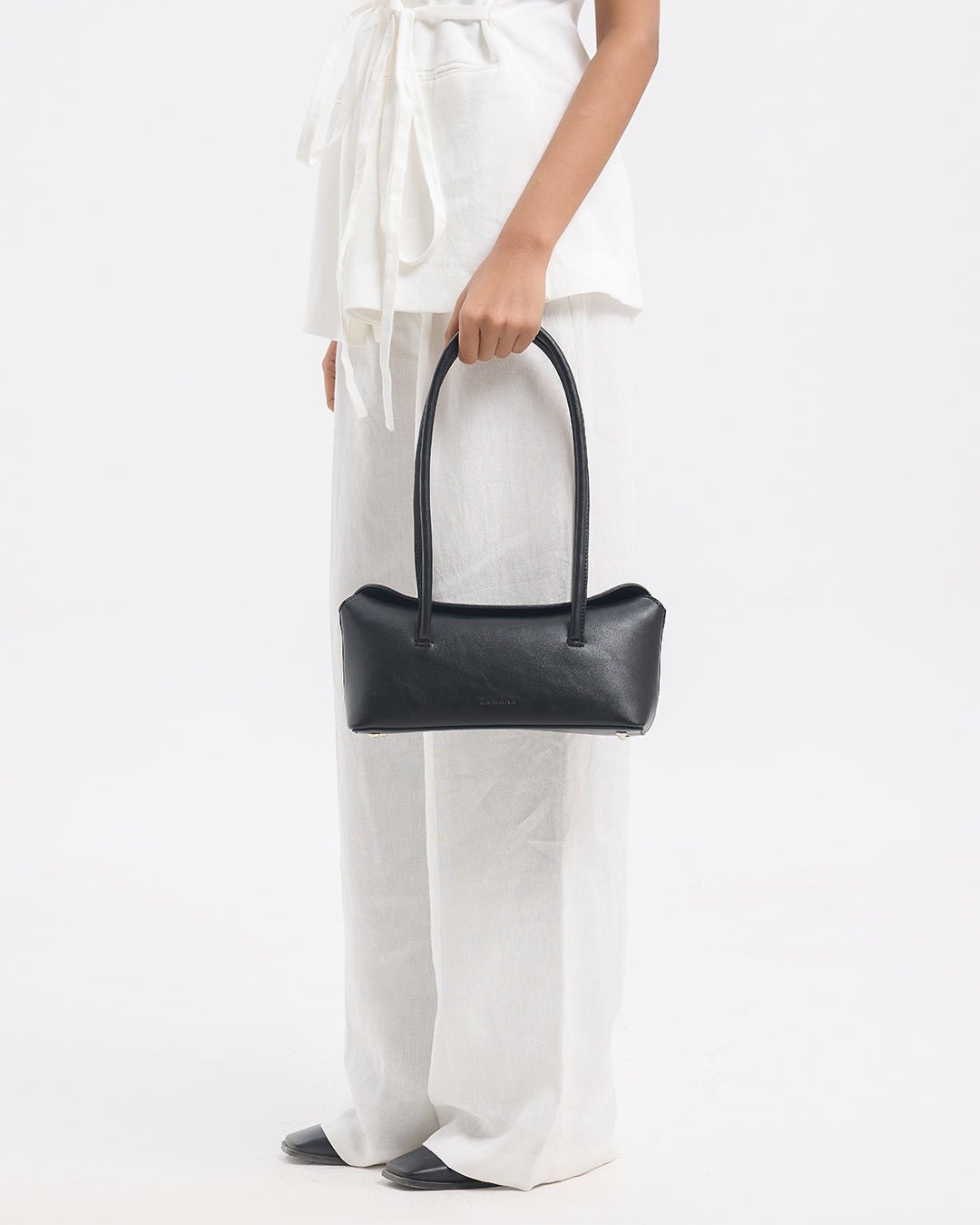 Black top-handle handbag with rounded rectangular shape held up