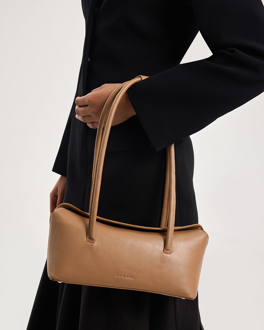 Caramel mini tote bag with top handles and front logo, held at side