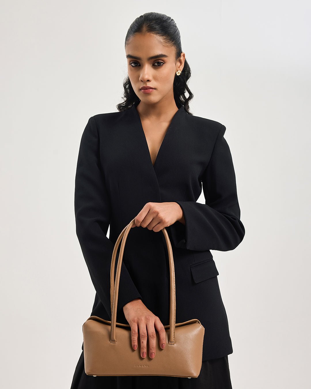 Caramel mini tote bag with rounded handles and front logo, carried on model