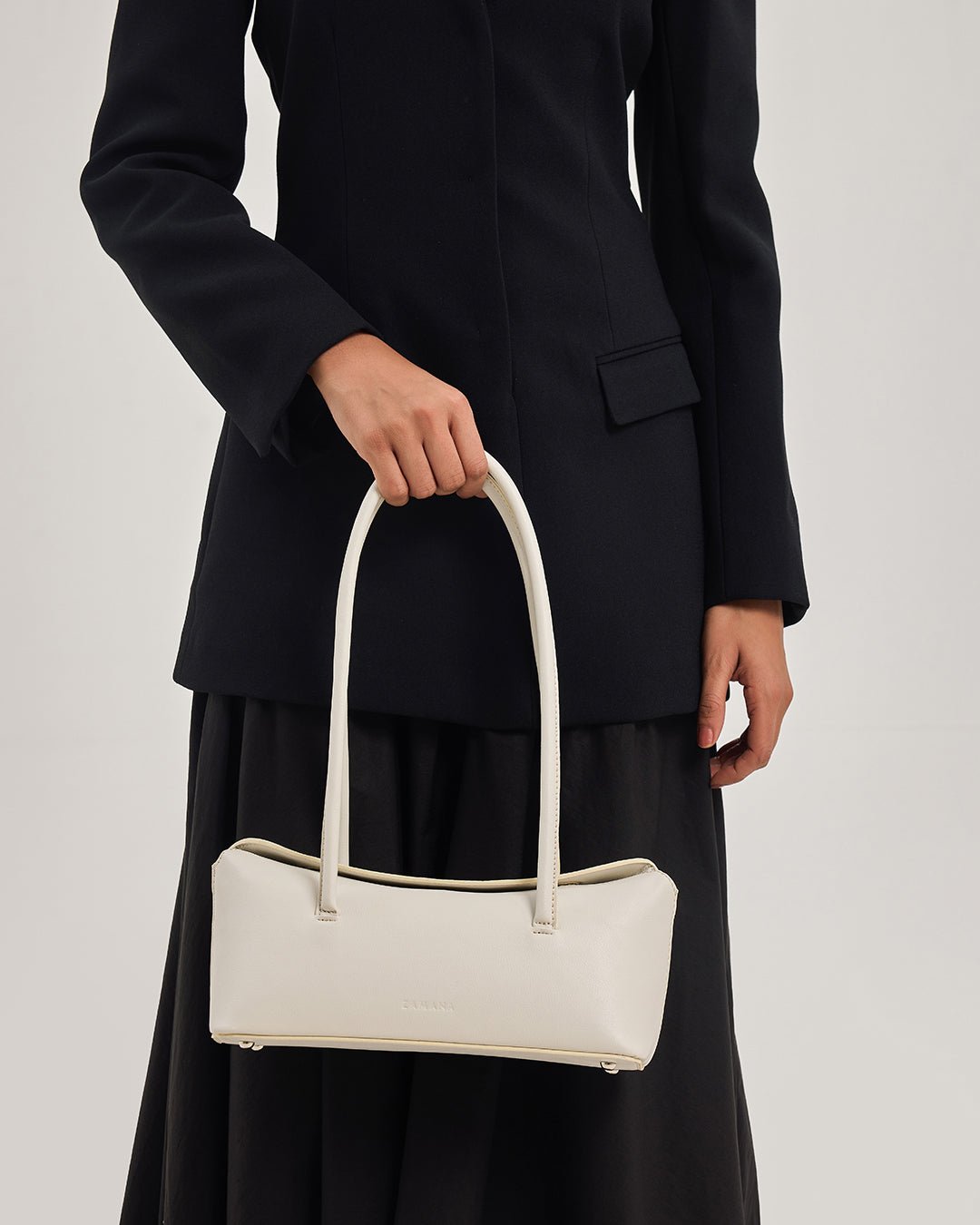 Cream tote bag carried over dark outfit with double top handles