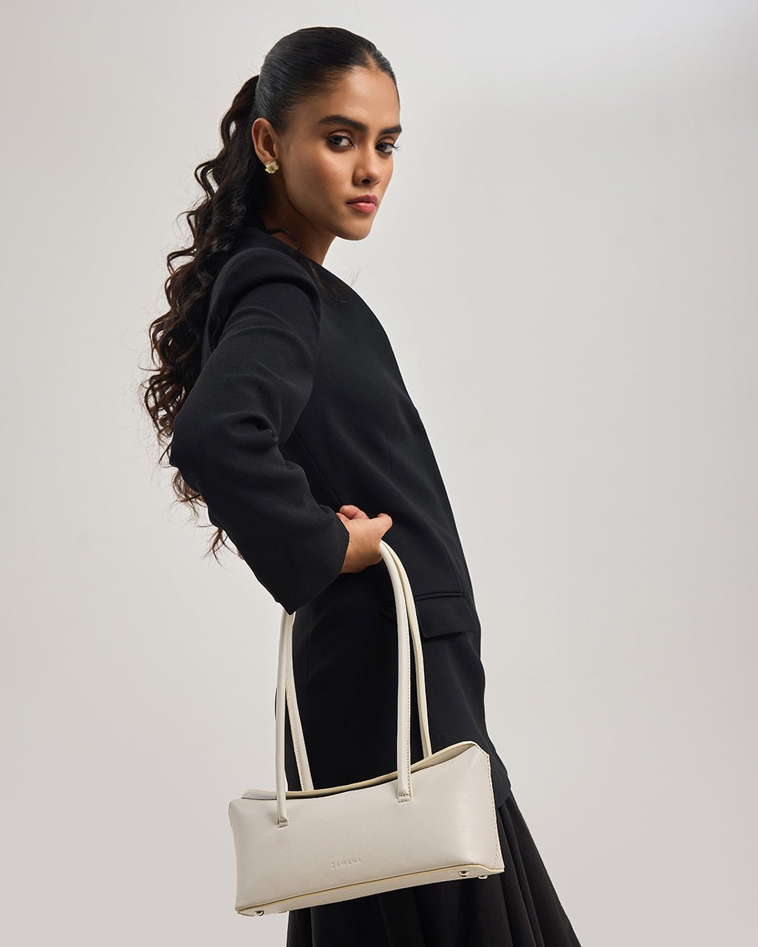 Model wearing a cream mini tote bag with U-shaped top handles