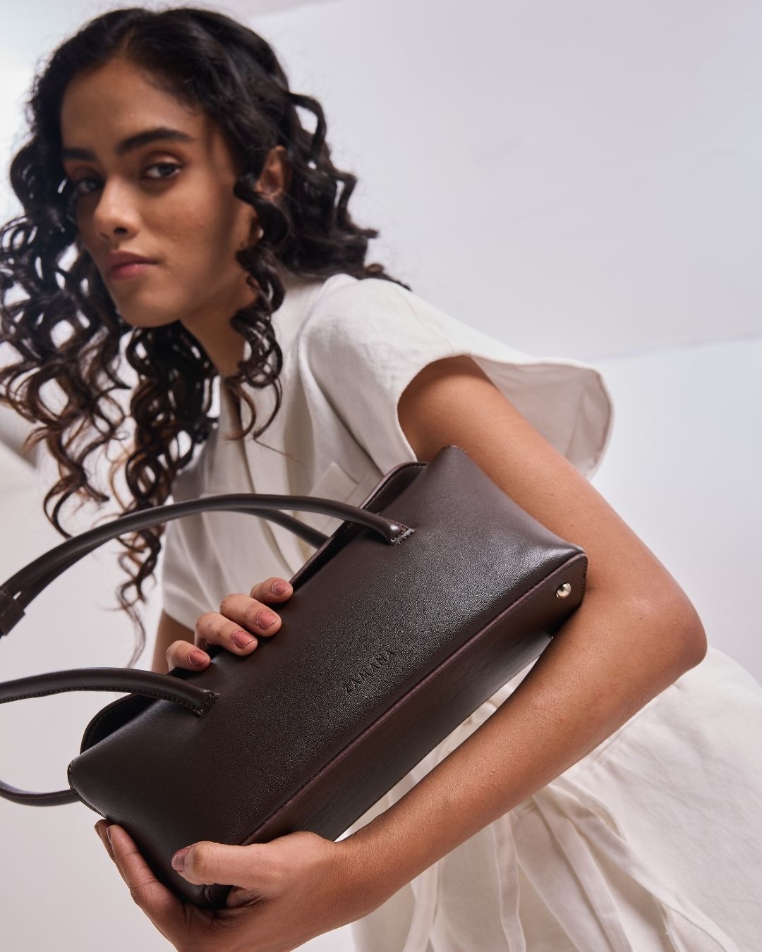 Dark brown leather-look tote bag, side view with wide base and two top handles