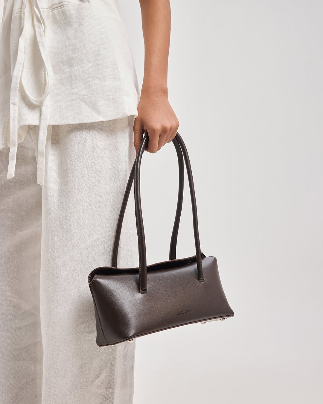 Dark brown small leather-look tote bag with two top handles and side grommet details