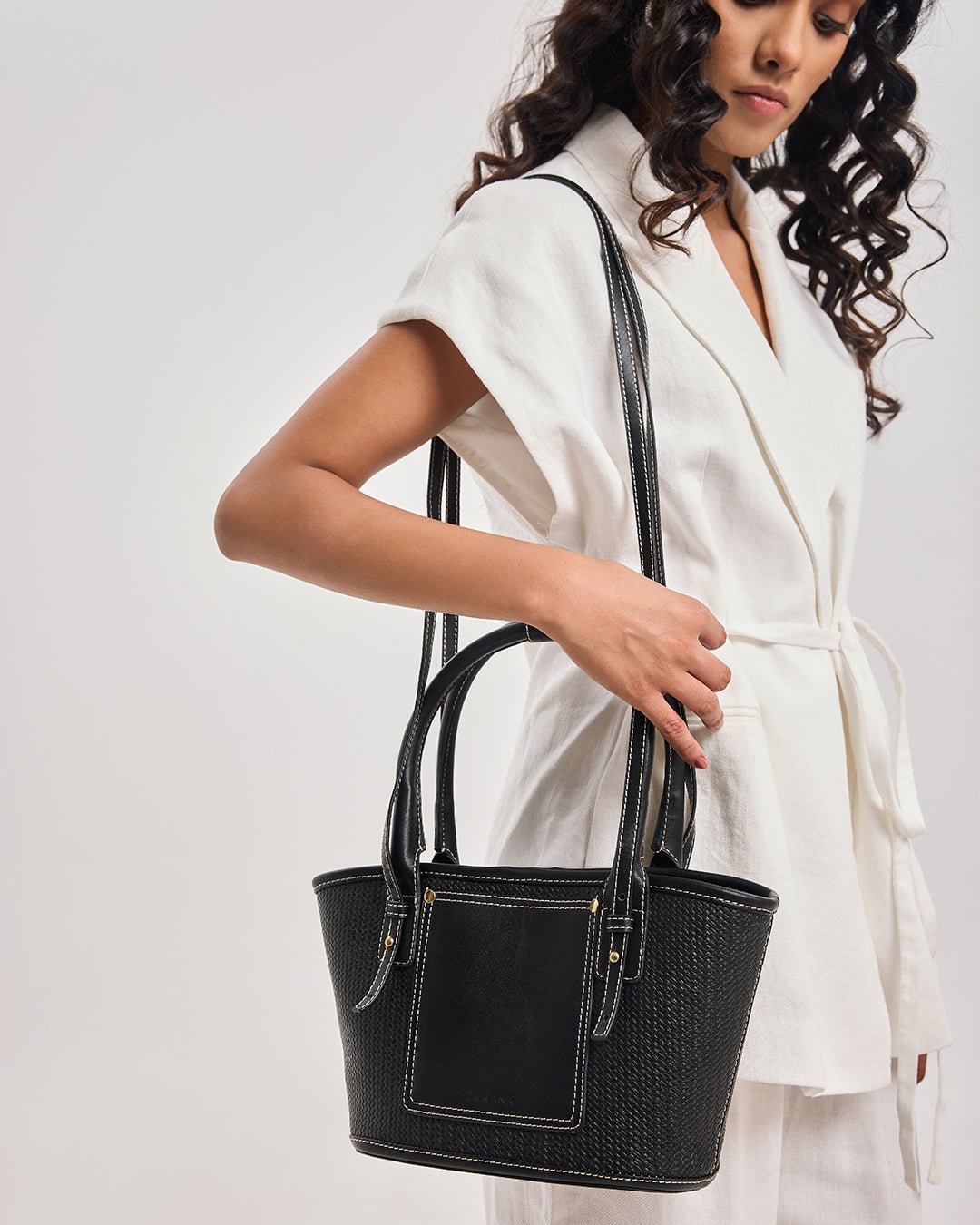 Black woven tote bag on model, top handles and rectangular front pocket