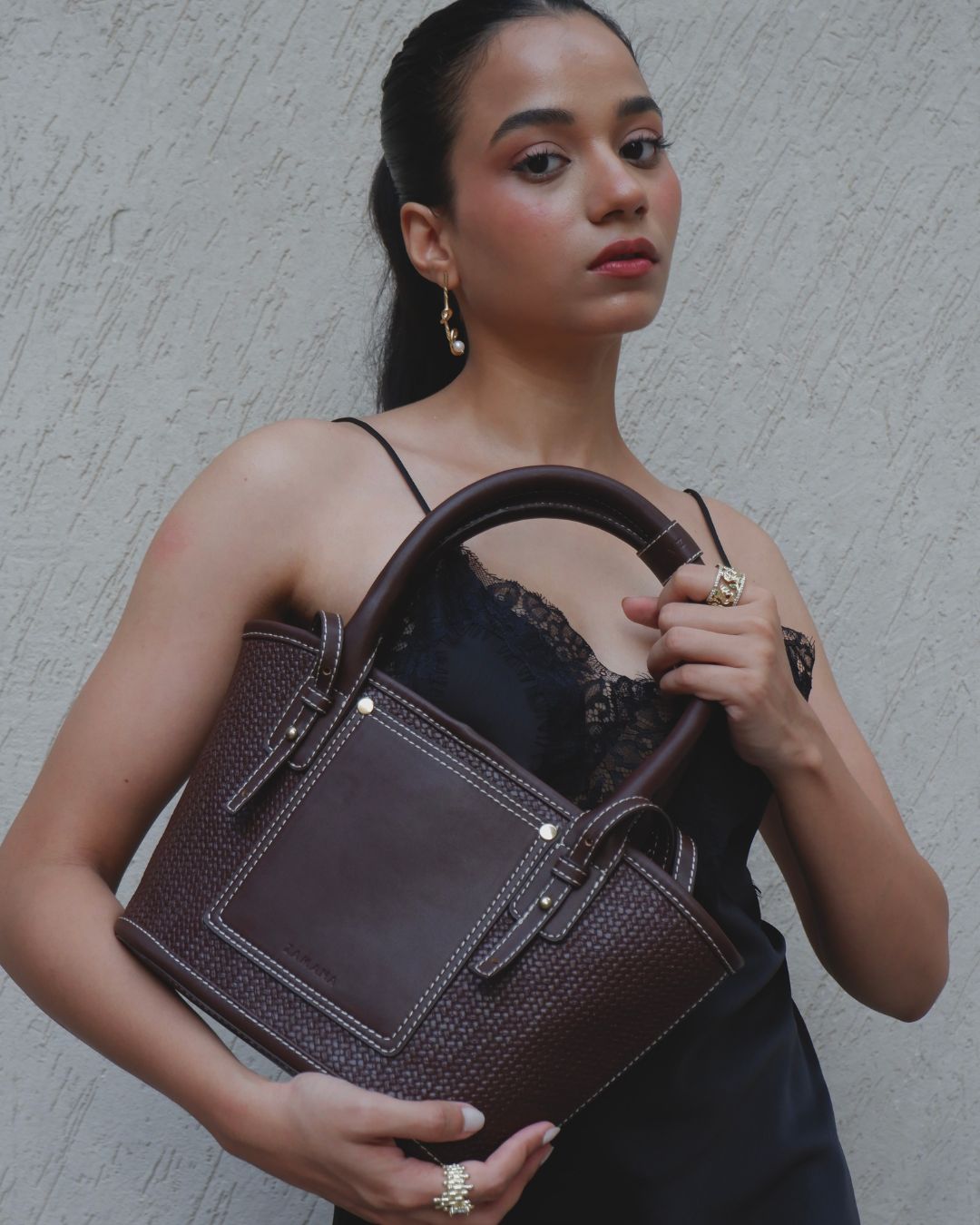 Brown textured tote bag with top handles and structured front panel, gold-tone hardware