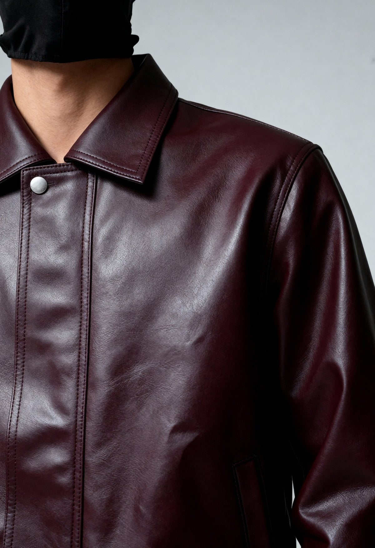 Burgundy leather bomber jacket close-up with stand collar and front seam stitching.