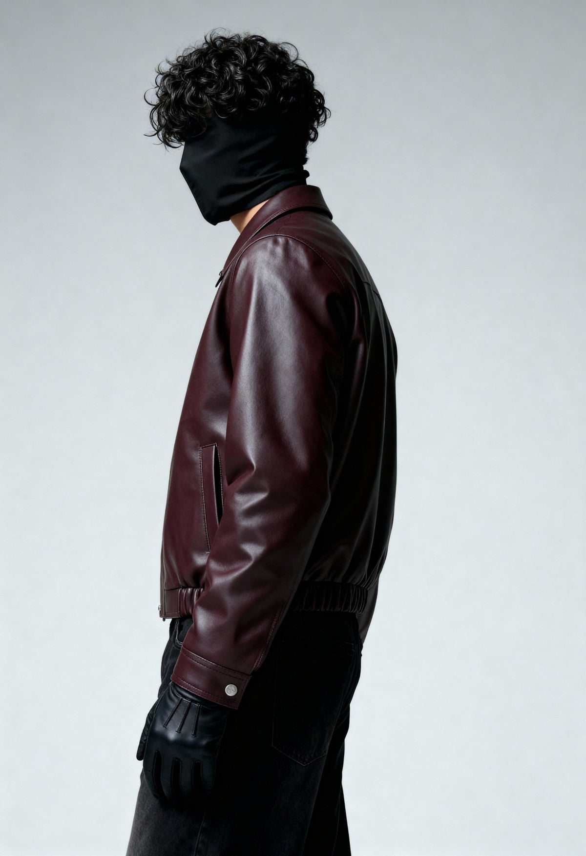 Burgundy leather bomber jacket side view with ribbed hem and zipper placket.