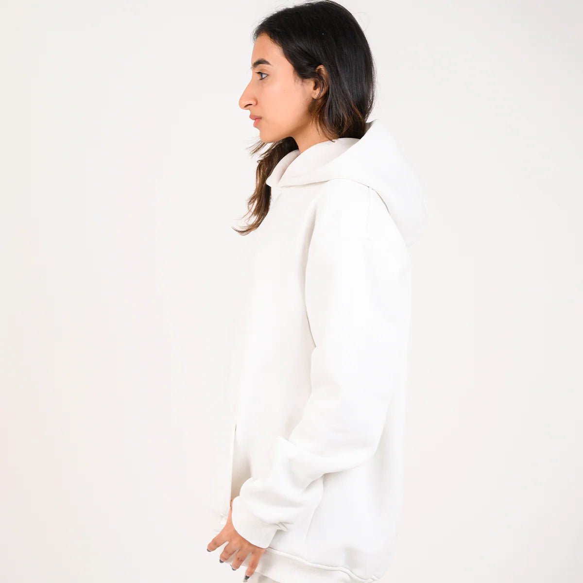 White pullover hoodie with hood and kangaroo pocket, side view on model.